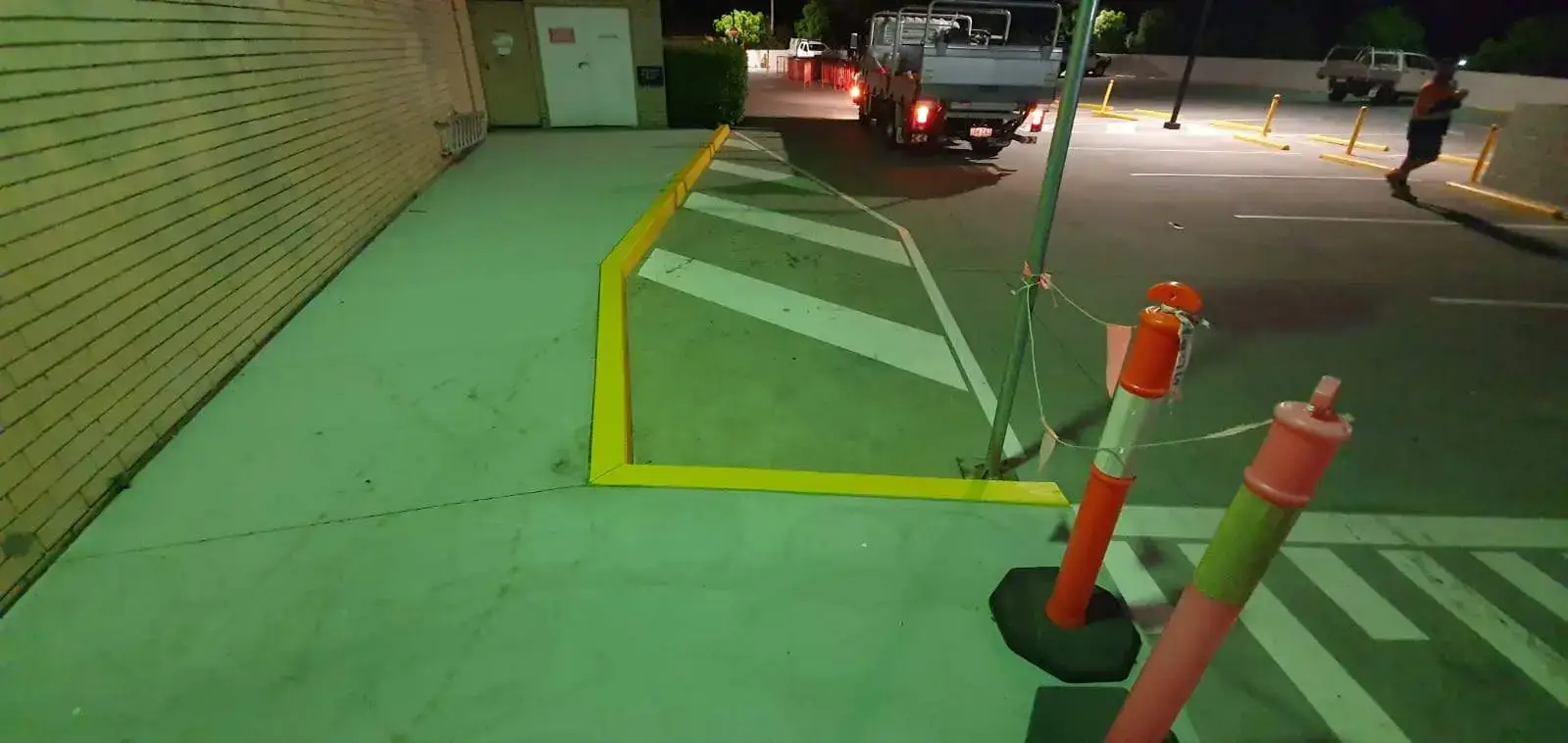 Yellow pedestrian safety markings and edge lines at night in a retail car park