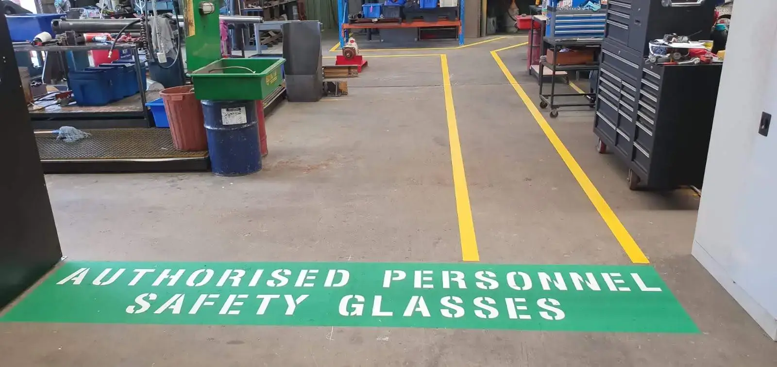 Green AUTHORISED PERSONNEL SAFETY GLASSES zone with yellow traffic lanes in a workshop