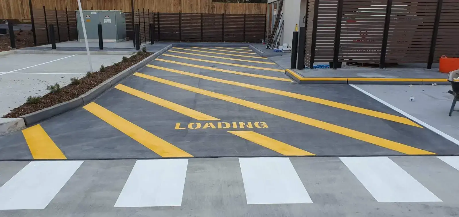 Yellow chevron loading zone markings with LOADING text and white pedestrian crossing stripes