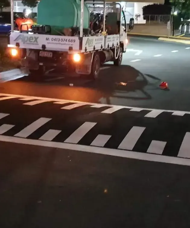 Apex Line Marking truck on site at night beside a freshly painted piano-key speed bump