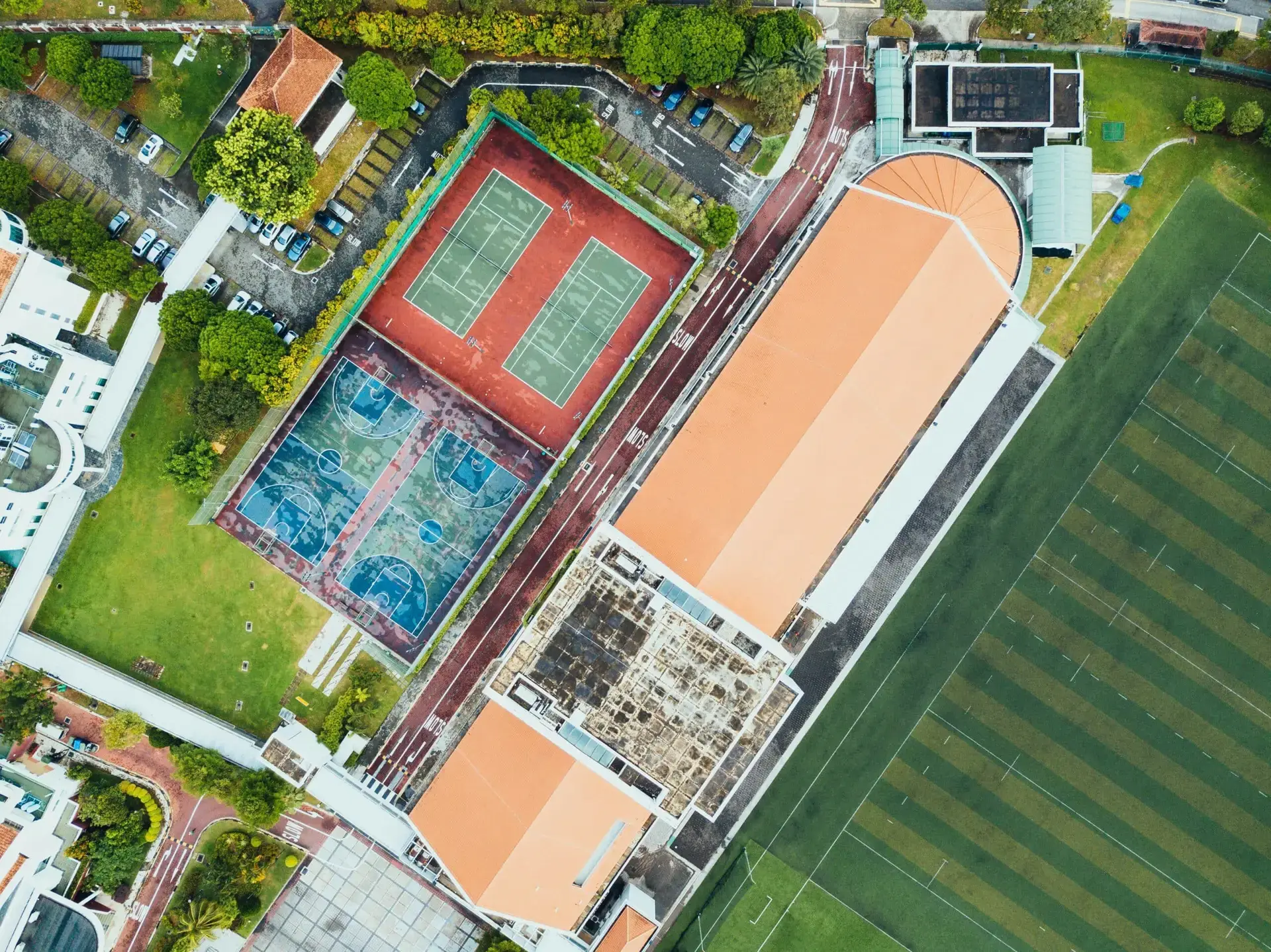 Aerial view of freshly marked tennis and basketball courts beside a school car park