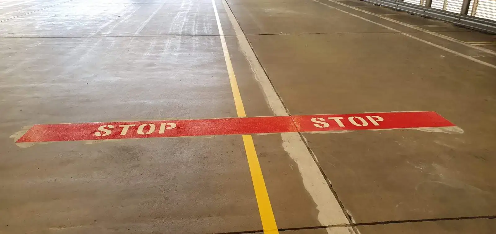 Red STOP text with yellow lane dividers in a shopping centre car park