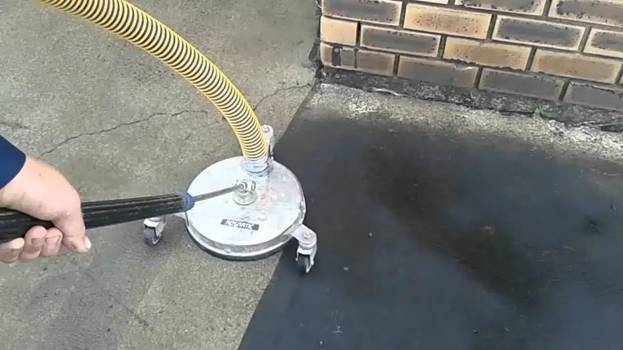 Rotary surface cleaner lifting years of grime from a concrete path