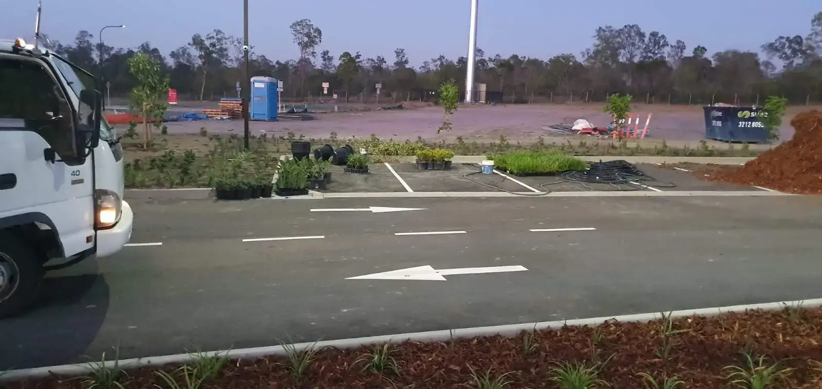 Fresh white directional arrows and bay lines on new asphalt at a construction site